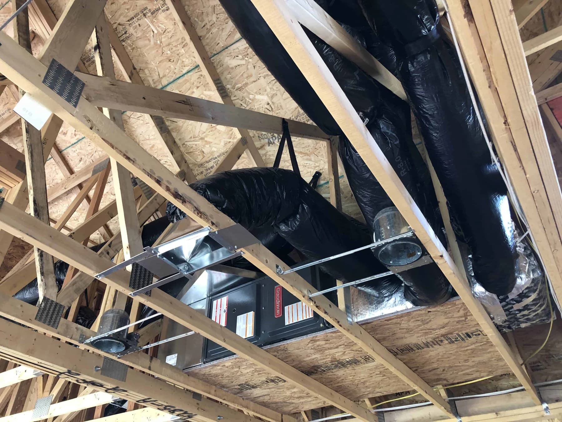 Furnace connected to flexible ductwork within exposed attic framing