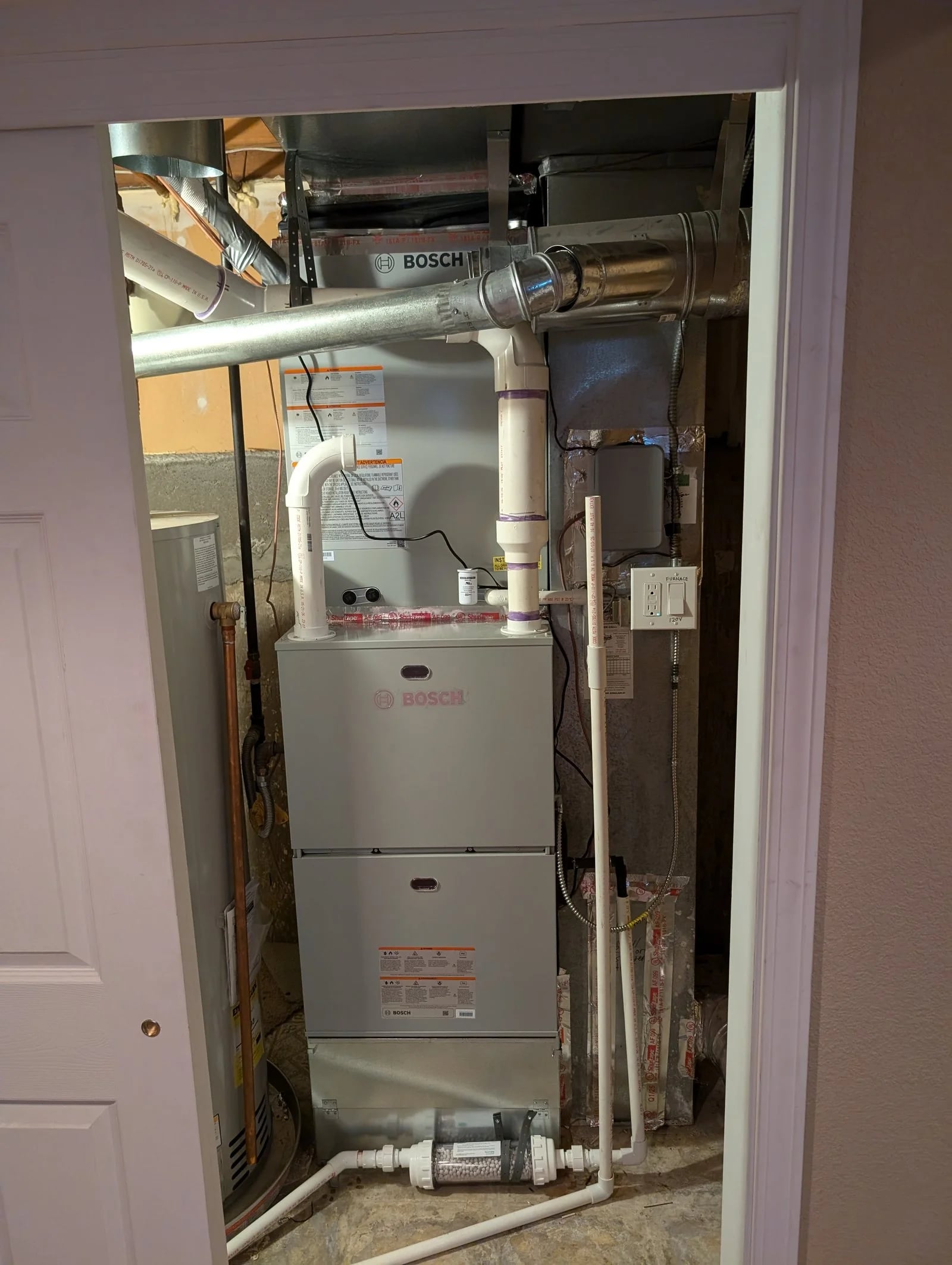 A Bosch furnace with new venting and ductwork in a small utility room