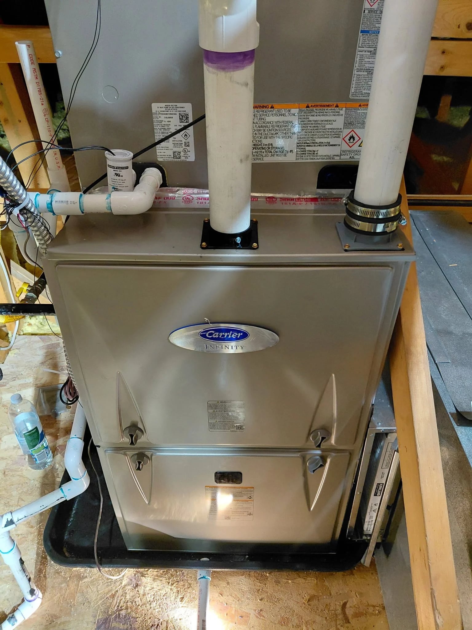 A Carrier Infinity furnace with new PVC venting and drain lines in a basement