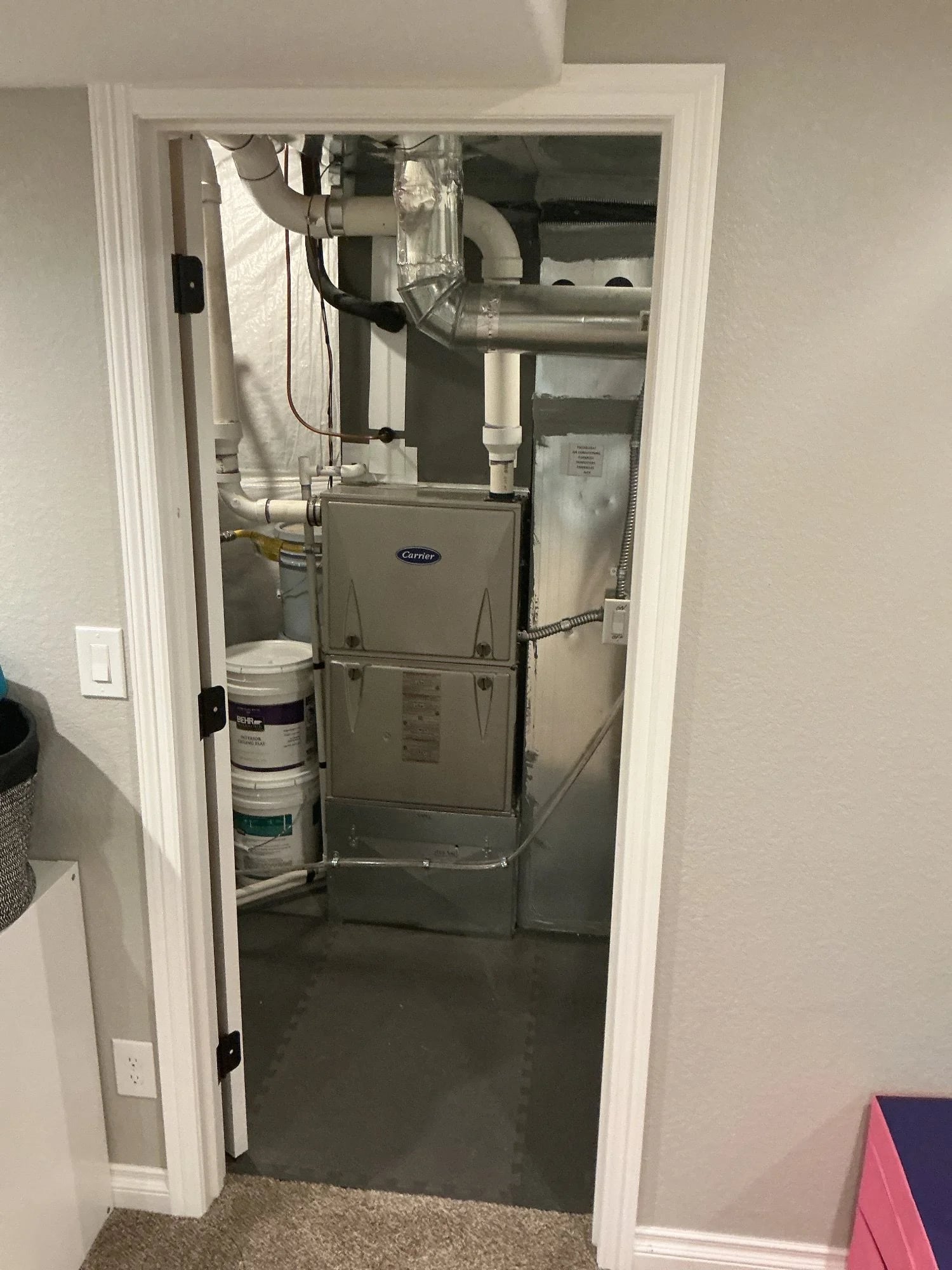 A Carrier furnace with new PVC venting, seen through the door of a basement utility closet