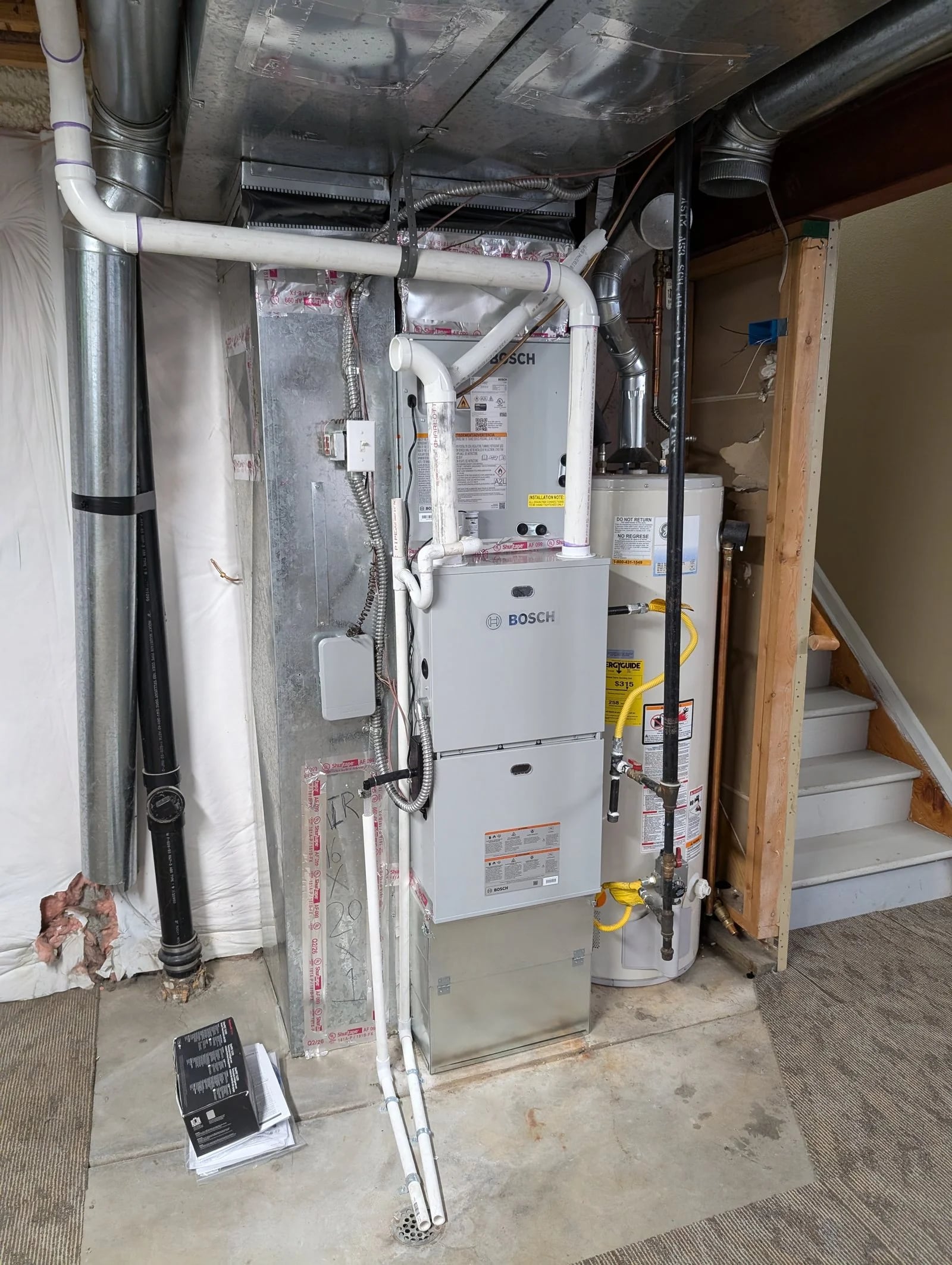A Bosch gas furnace and indoor coil with new PVC venting in a basement